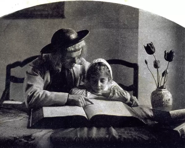 A young man and a little girl in seventeenth century dress, seated at a table reading the Bible