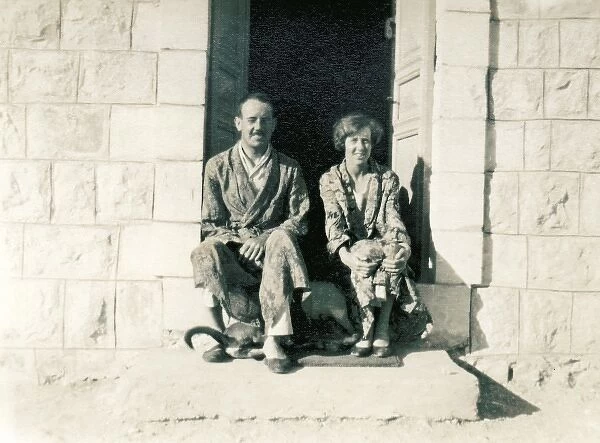 Couple in pyjamas sitting on a stone step in the sun