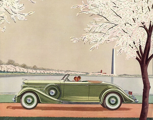 A fine green open-top convertible 1920s sports car passes the Washington Monument
