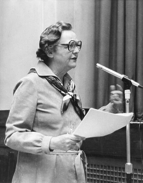 Jessica Mitford speaking at a microphone