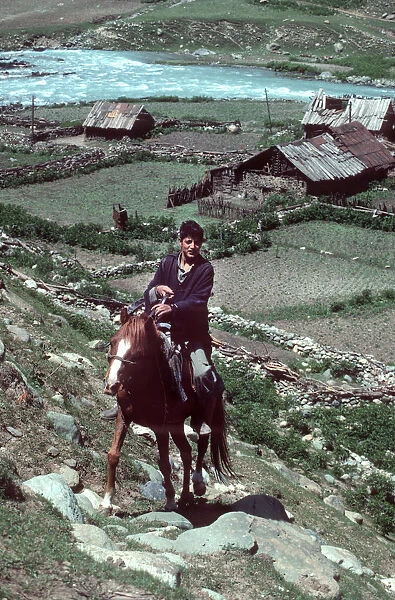 Kashmir - young horseman rides up steep hill