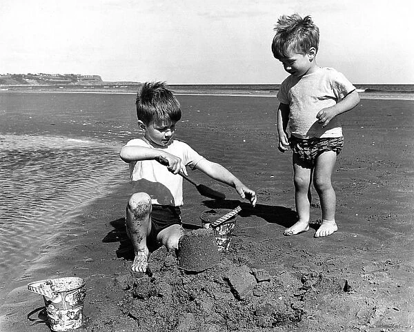Two little boys making sandcastle on beach