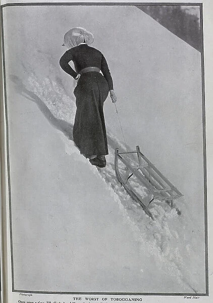 Photograph of woman climbing snowy hill, pulling toboggan behind her, at St Beatenberg, Lake Thun, Switzerland, by Ward Muir. Captioned, Jill - to Date! and The Worst of Tobogganing'. Date: 1910