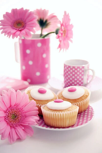 Tea party. Decorated cakes on a saucer surrounded by gerbera flowers