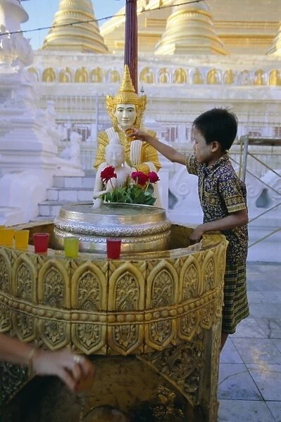A boy places offerings to the Buddha, Shwedagon Paya (Shwe Dagon pagoda)