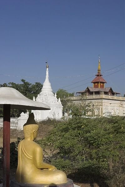 Buddha image sitting under parasol near pagodas, Salay, Myanmar (Burma), Asia