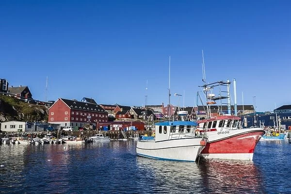 Commercial fishing and whaling boats line the busy inner harbor in the town of Ilulissat, Greenland, Polar Regions