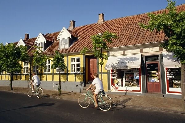 Cyclists pass small shop in Ronne, Bornholm Island, Denmark, Scandinavia, Europe