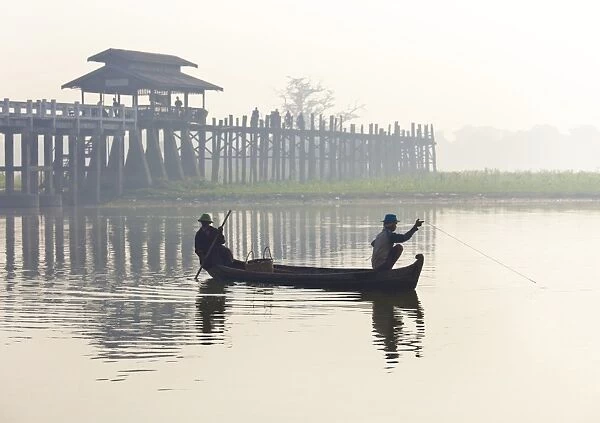 Fisherman on Taungthaman Lake in mist at dawn with U Bein Bridge, the worlds longest teak foot bridge spanning 1300 yards, Amarapura, near Mandalay, Myanmar (Burma), Asia