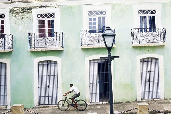Man riding bicycle in front of old colonial house, Sao Luis, Maranhao, Brazil