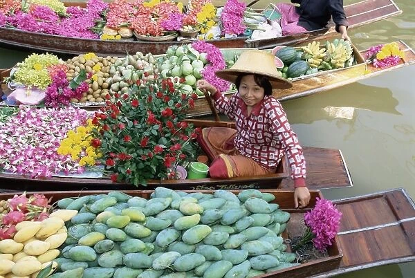 Market trader in boat selling flowers and fruit