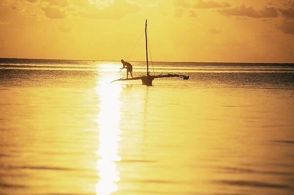 Outrigger canoe and fisherman in silhouette at sunrise off Jambiani, Zanzibar