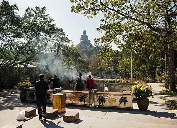 People lighting incense at Po Lin Monastery with Big Buddha statue in background