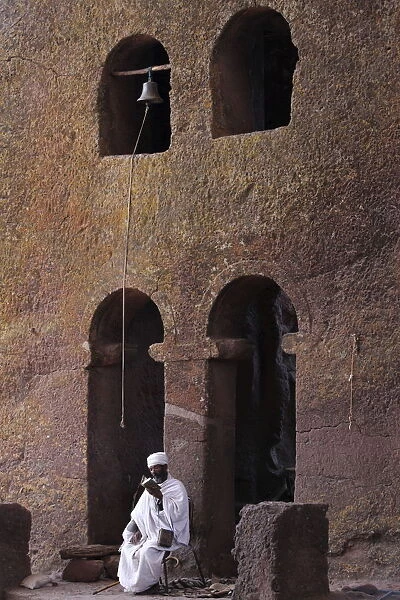 Priest reading a Bible in Bet Maryam church courtyard, UNESCO World Heritage Site