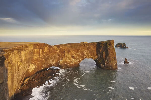 A rock arch on Dyrholaey Island seen in sunset sunlight, near Vik, south coast of Iceland, Polar Regions