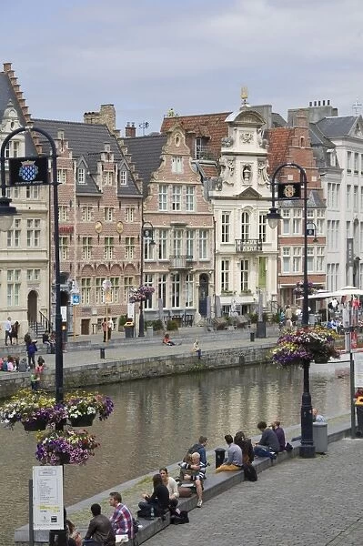 Students relaxing along the banks of the Graslei, Baroque style Flemish gables in the background, Ghent, Belgium, Europe