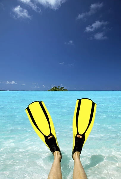 Tropical island and person wearing flippers sitting in sea, Maldives, Indian Ocean, Asia
