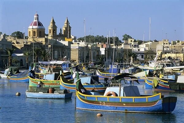 View across harbour with traditional Luzzu fishing boats, Marsaxlokk, Malta