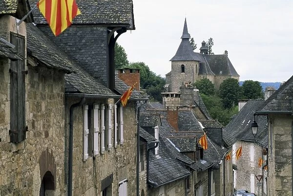 View along village street to church, with colourful flags, Turenne, Correze