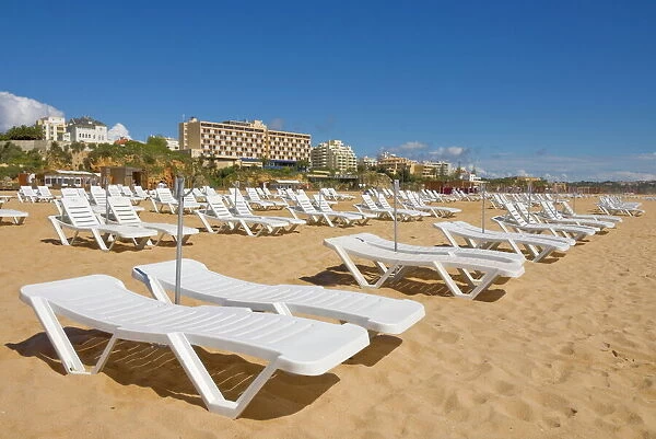 Empty white sun lounger sunbeds on Praia da Rocha beach, Portimao, Algarve