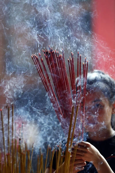 Woman praying with burning incense sticks, Ong Bon Pagoda, Taoist Temple