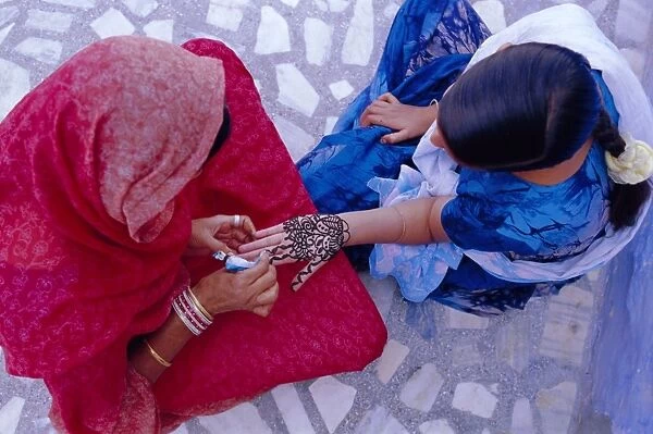 Womans hand being decorated with henna design