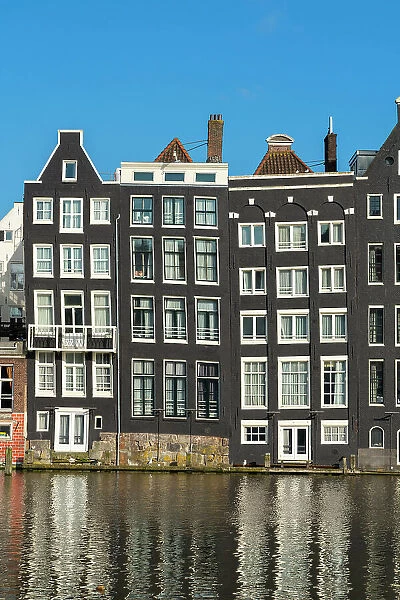 Dancing houses near river against sky, Damrak, Amsterdam, Netherlands