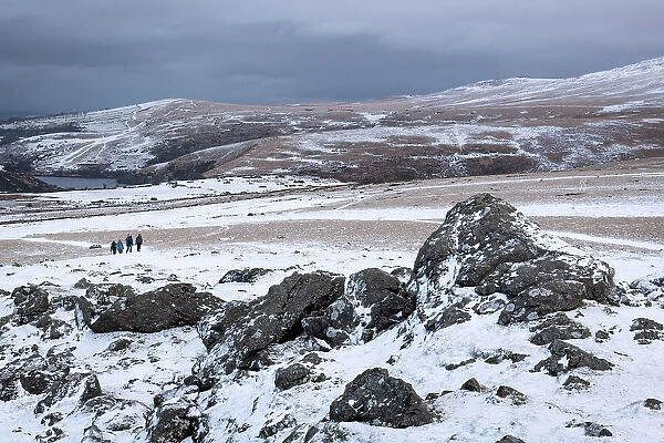 Hikers on Sourton Tor on a snowy winter day, Dartmoor National Park, Devon, England. Winter (January) 2023