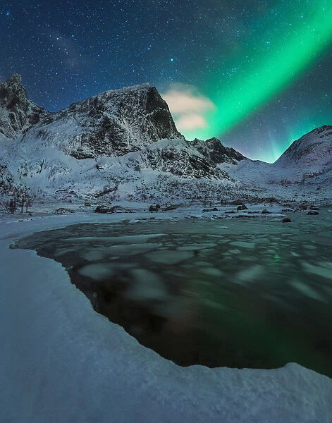 Northern lights over a partly frozen fjord during winter in the Lofoten islands, Norway