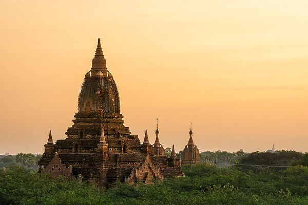 Old pagoda amidst trees against orange sky during sunrise, Bagan, Mandalay Region