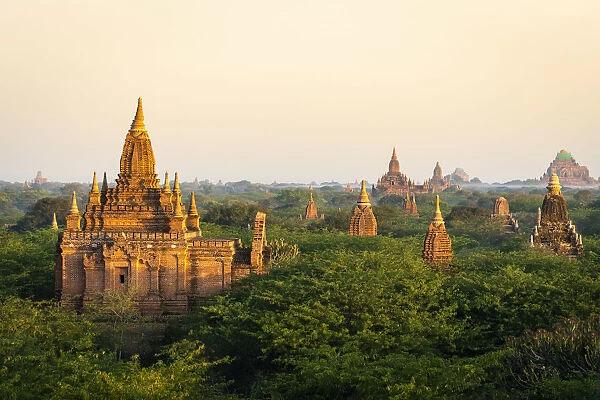 Old pagodas amidst trees against sky during sunrise, Bagan, Mandalay Region, Myanmar