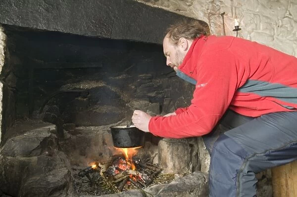 A man cooking in Peanmeanach Bothy near Mallaig in Scotland