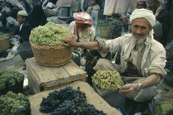 10007916. YEMEN Saada Grape vendor in Souk holding green grapes