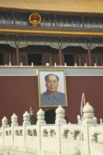 10125033. CHINA Beijing Policeman standing under a picture of Chairman Mao