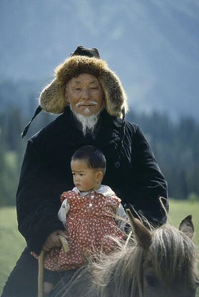 20065923. CHINA Xinjiang Kazakh grandfather and granddaughter on horse