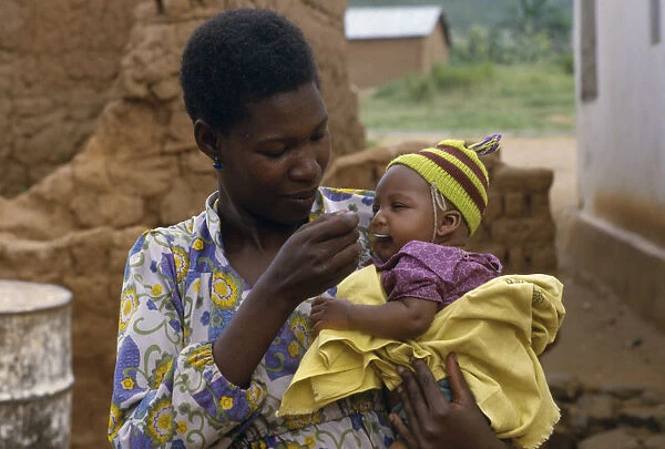 20075956. TANZANIA People Mother feeding baby daughter with a spoon