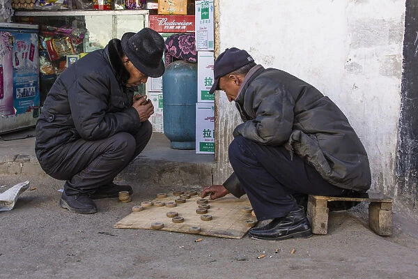Tibetan men playing checkers on the sidewalk in a neighborhood in Lhasa, Tibet