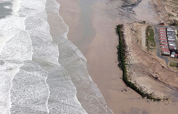 An aerial view shows a sea wall on the beach that protects camping sites