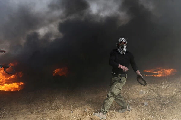 Demonstrator passes by burning tires during clashes with Israeli troops at a protest