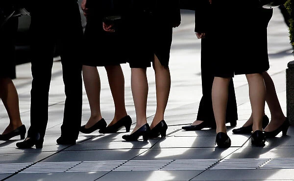 Female office workers wearing high heels, clothes and bags of the same colour are seen at