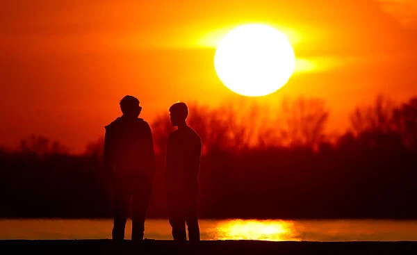 People stand on the bank of Volga river during the sunset in Samara
