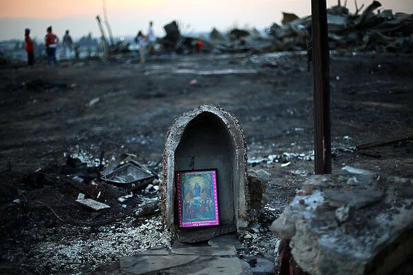 A religious image is seen in front of debris of an immigrants shacks camp after an
