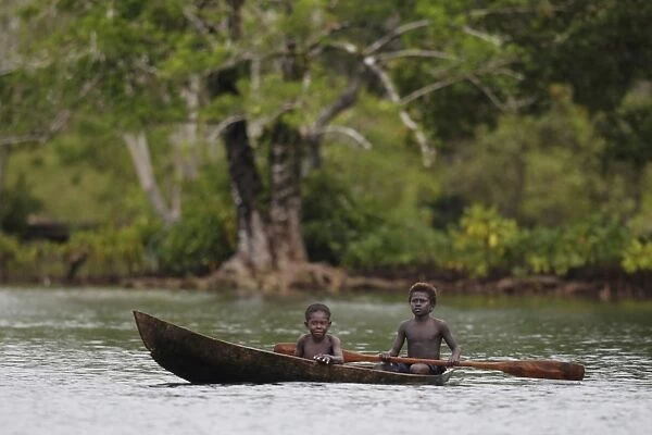 Two boys paddling dugout canoe, Kolombangara Island, Solomon Islands, April
