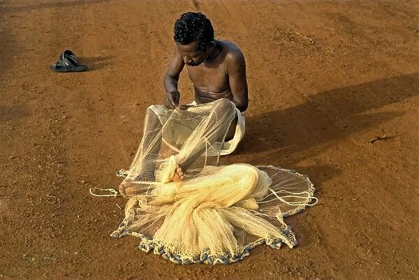 Fisherman mending nets on beach, Trivandrum, Kerala, India