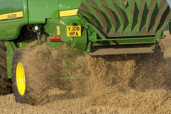 John Deere combine harvester, harvesting Barley (Hordeum vulgare) crop, discharging chaff and straw waste from back