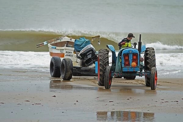 Tractor and trailer landing crab fishing boat on beach, Cromer, Norfolk, England, august