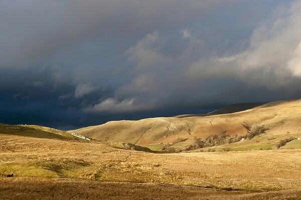 View of fells in evening sunlight, with distant stormclouds, near Kirkby Stephen, Cumbria, England, March