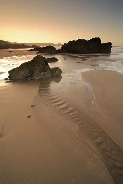View of rocks on sandy beach at low tide, at sunrise, Whitsand Bay, Cornwall, England