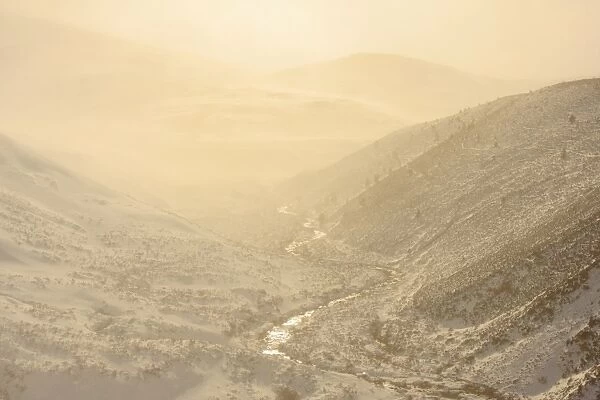 View of upland river valley with Spindrift of fine snow blown off by wind at sunset, Allt Mor, Glenmore Forest