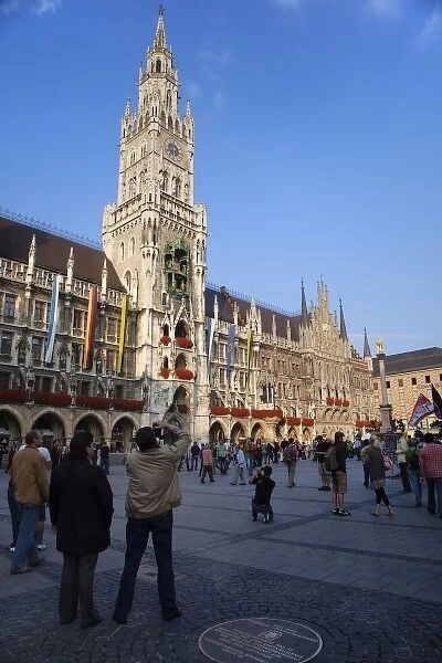 Germany, Munich. Tourists in the Marienplatz with glockenspiel clock on left